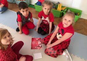 Dzieci siedzą przy ułożonych puzzlach z sercami